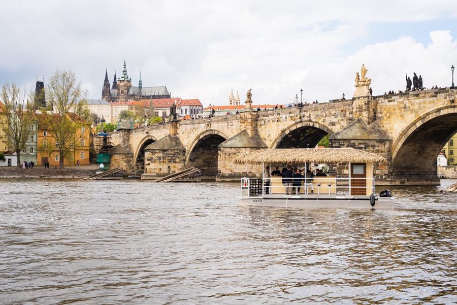 Prague: Party Tiki Boat Sightseeing Cruise with Drinks - A Tiki Boat with Prague in the background